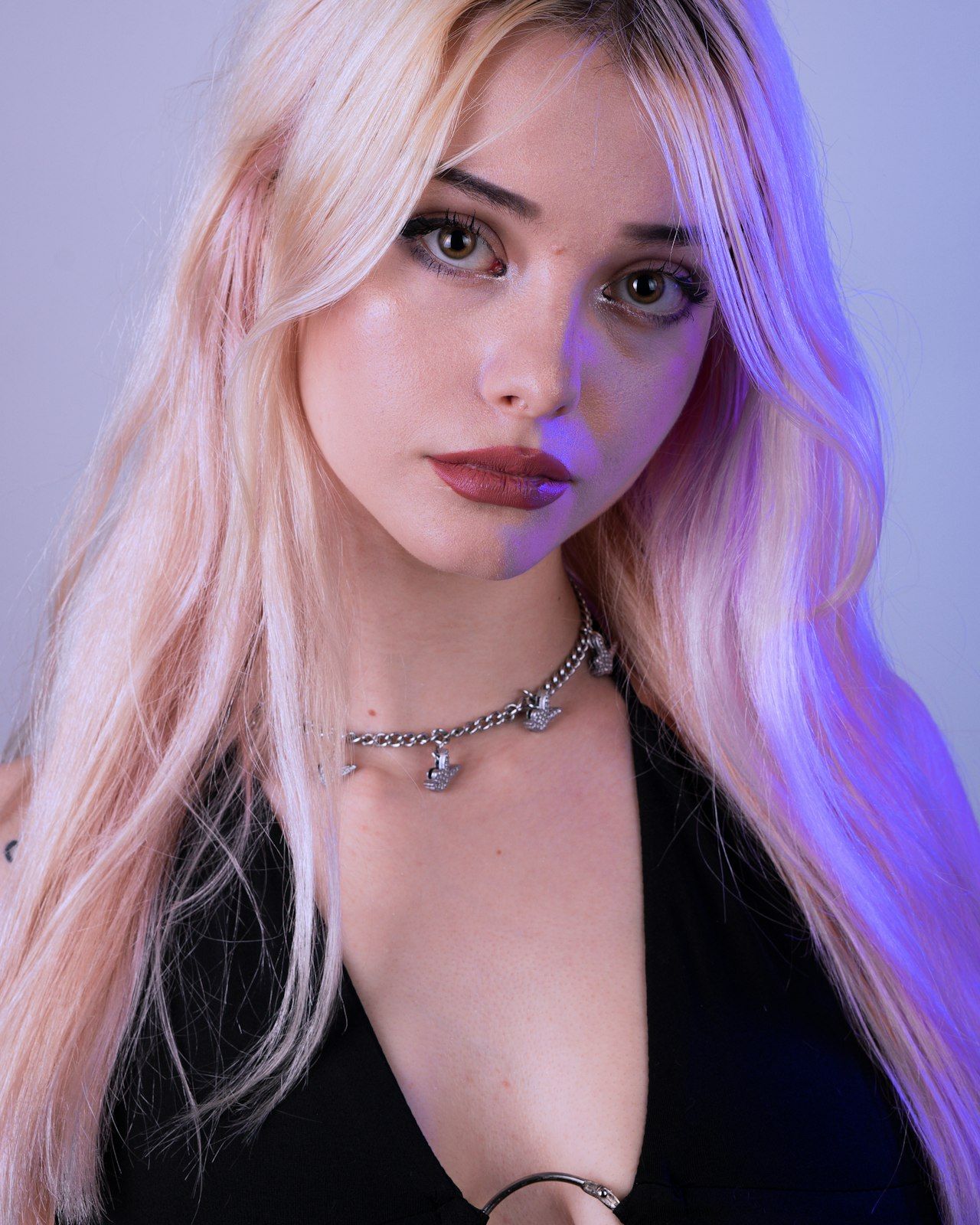 A portrait lit in magenta and violet gel light, silver jewellery catching the colour.